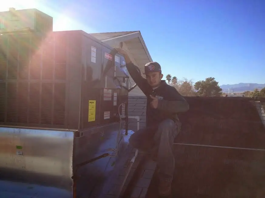 HVAC technician performing AC Tune-Up on a rooftop unit in Napoleon